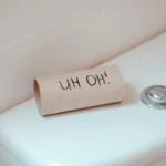 an empty toilet paper role on the back of a toilet